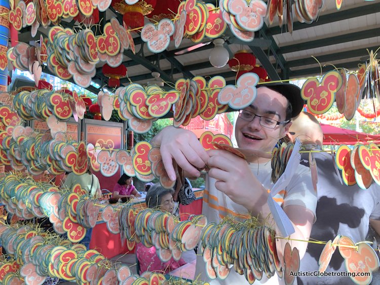 Attending Disneyland's Lunar Year Celebrations with Autism tying his paper wish on the wall