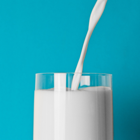 Tall glass cup in front of a turquoise backdrop. 